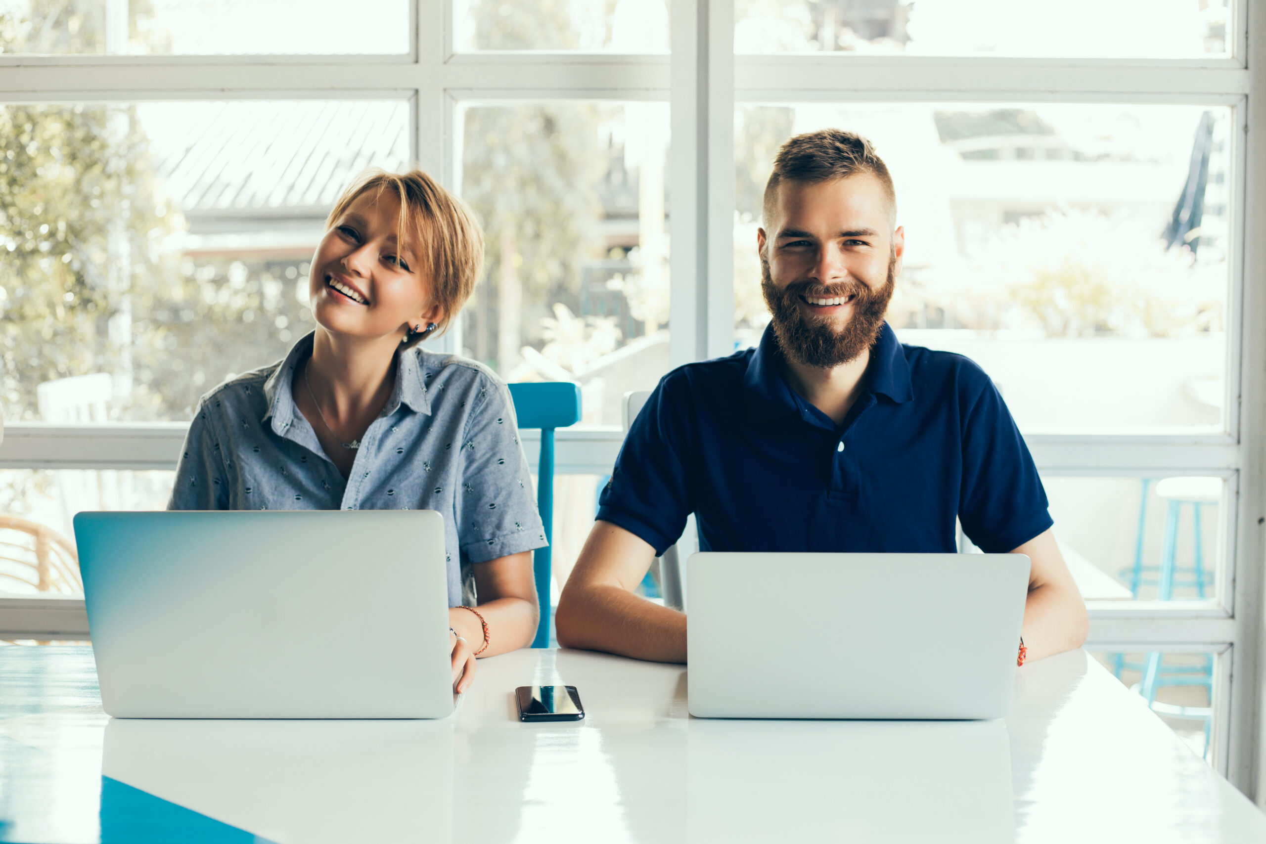 Young Couple Working On Laptops In A Cafe Doing A Project, Conferring, Freelancers, Smiling, Managers In The Company